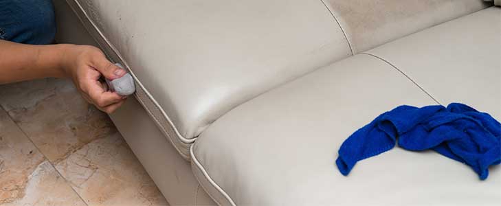 This image shows a man using a cleaning solution on the leather sofa.